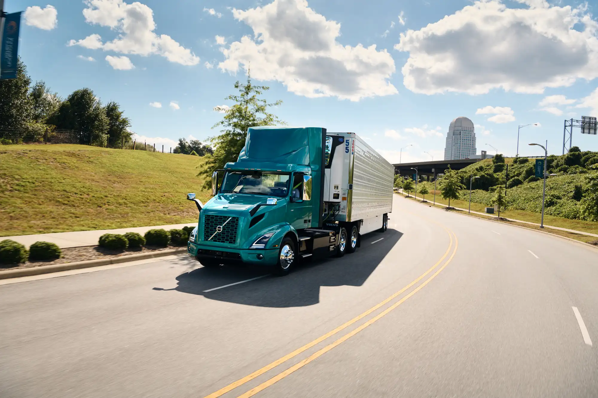 Blue Volvo VNR Electric truck driving on a road on a sunny day
