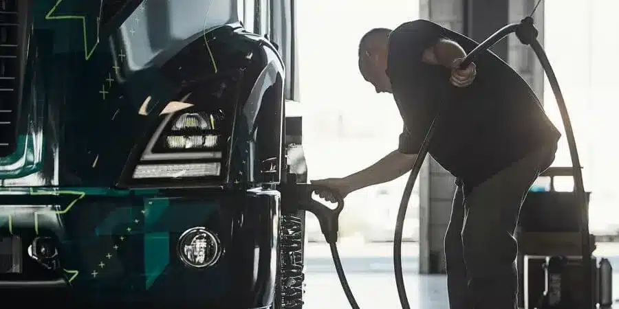 Man plugging in Volvo VNR battery electric truck to charge.